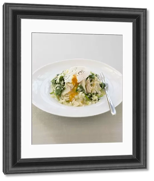 Haddock risotto with spinach and poached egg on a plate, with a fork