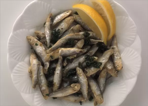 Plate of Friture de la Loire, deep-fried whitebait served with lemon slices, view from above