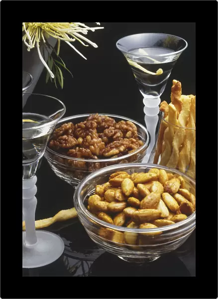 Bowls of nuts and cheese sticks and two glasses of aperitifs
