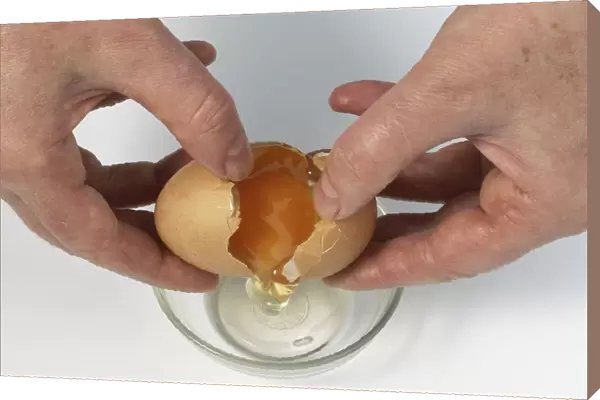Raw egg being cracked over glass bowl, close up