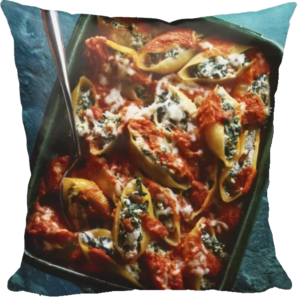 Pasta shells stuffed with spinach and cheese and topped with tomato sauce, in a baking dish, view from above