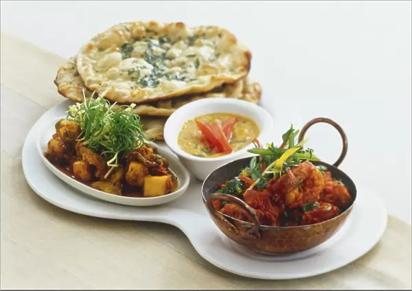 Bowls of prawns cooked in tomatoes (Kadhhai Jhinga), lentil curry (Tadka Dal), paneer and baby corn with ginger, and stack of flat bread, arranged on a serving dish