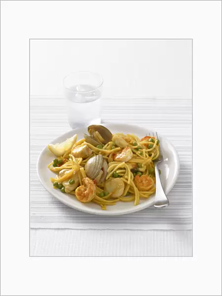 Fideua, a Spanish pasta dish of spaghetti, mixed seafood and peas, served with a glass of water, close-up