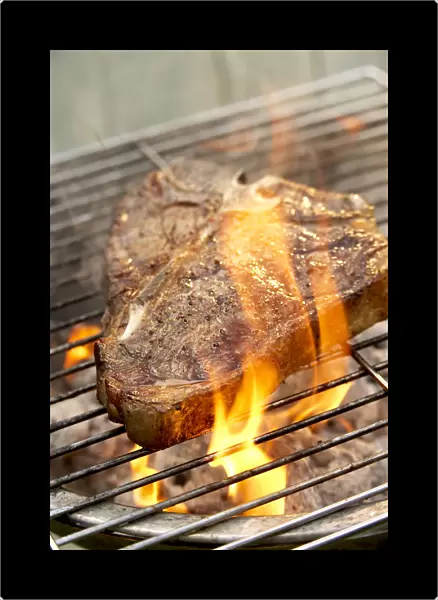 Fire flaring up around steak on barbecue grill