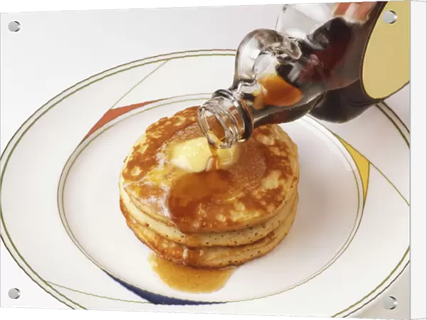 Pouring maple syrup over pancakes