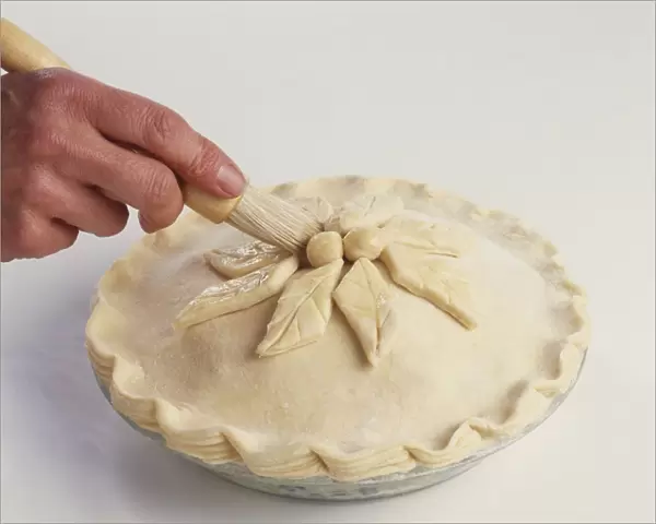 Brushing top of dessert pie with milk