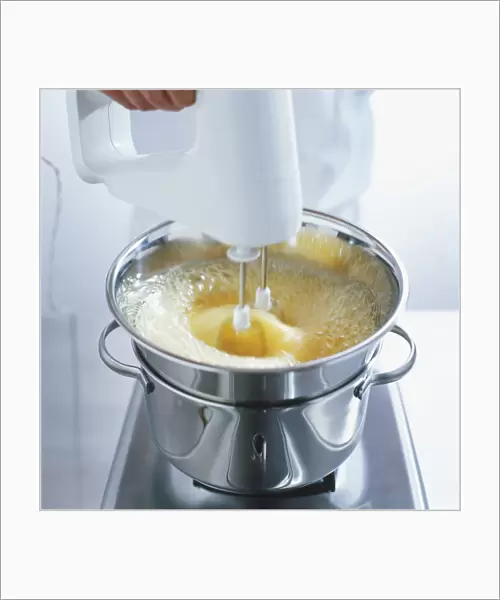 Using an electric whisk to mix eggs, sugar and honey in a heatproof bowl