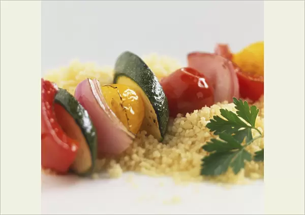 Row of sliced, fried vegetables on bed of couscous, garnished with coriander leaf