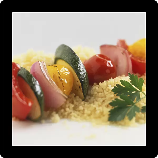 Row of sliced, fried vegetables on bed of couscous, garnished with coriander leaf