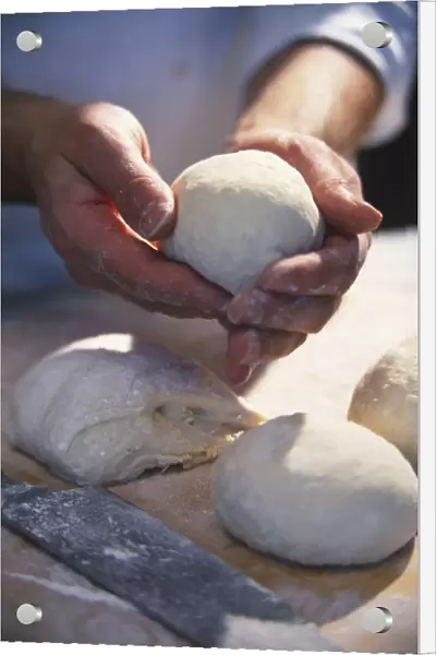 Hand shaping dough into ball, fresh dough, dough balls and pizza peel on kitchen surface