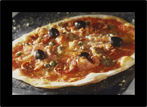 Pizza Capricciosa, round pizza with light crispy crust, topped with olives, ham, salami, capers and tomato sauce