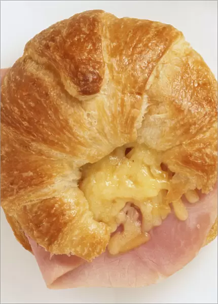 Above view of croissant filled with grated cheddar cheese and ham