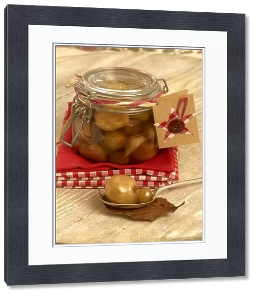 Pickled onions in a jar, with two on spoon in foreground