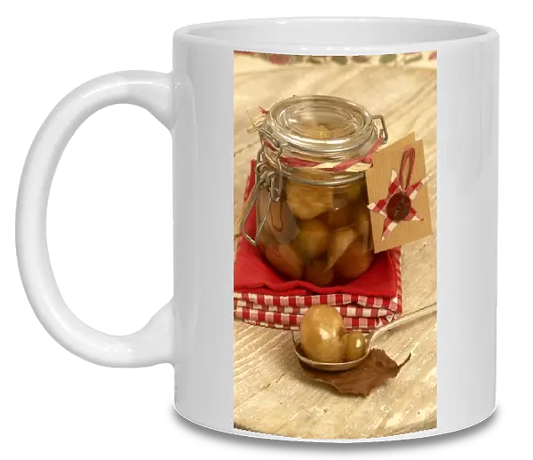 Pickled onions in a jar, with two on spoon in foreground