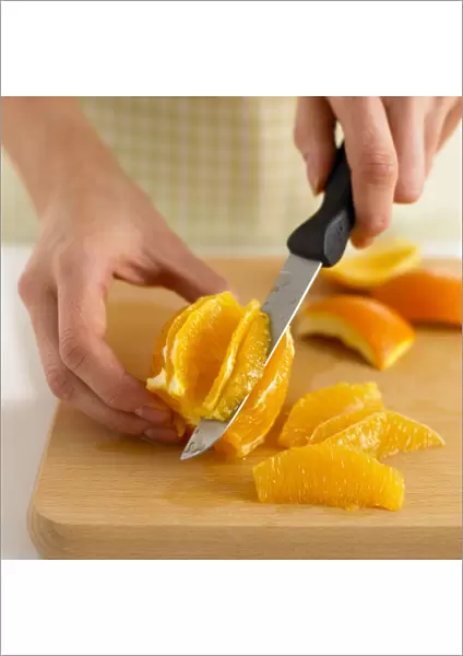 Woman using knife to segment an orange