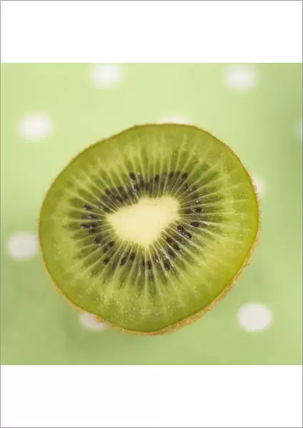 Half cut kiwi fruit on green polka dot tablecloth