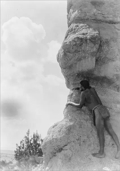 San Ildefonso man peering from behind large rock formation, c1927. Photograph by Edward Curtis