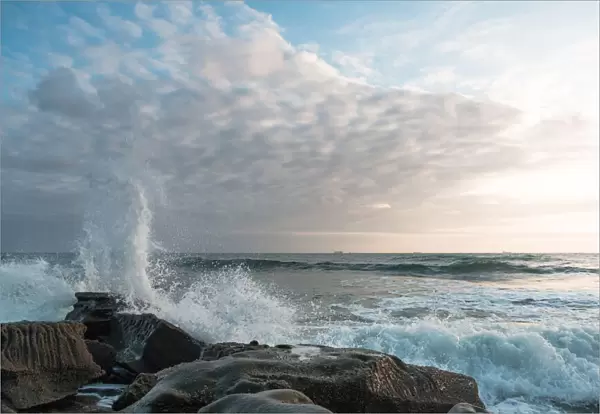 White clouds with waves crashing on a rock formation at Moffat Beach, Queensland