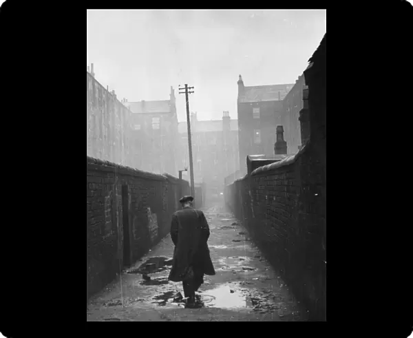 A man walking through a backstreet of the Gorbals area of Glasgow