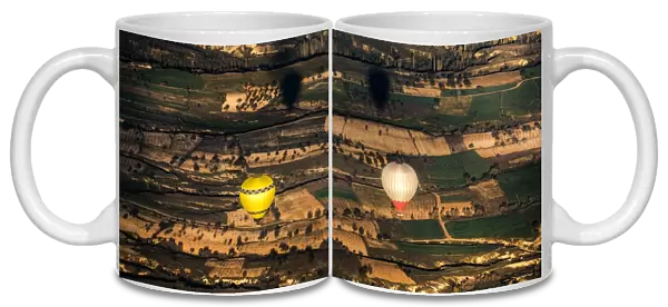 Two balloons floating over Cappadocia landscape