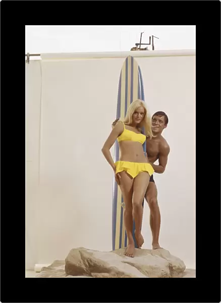 Man holding surfboard behind woman