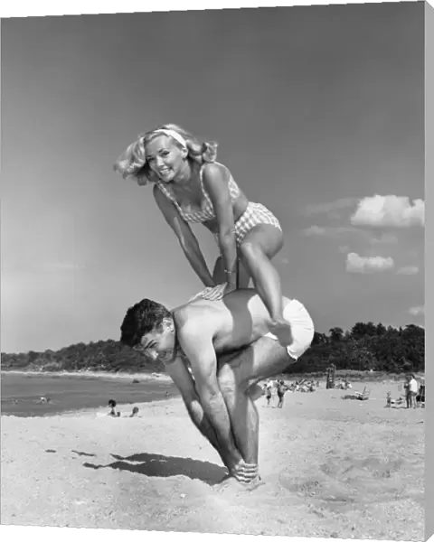 Couple playing leapfrog on beach