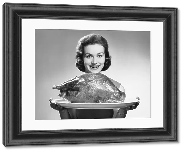 Woman holding platter with roast turkey
