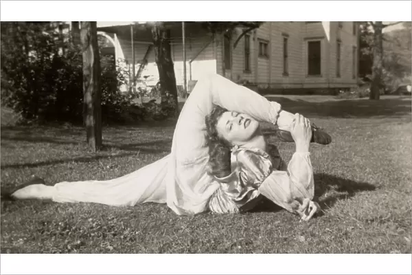 Flexible Woman in a Garden Bending Her Leg Above Her Head
