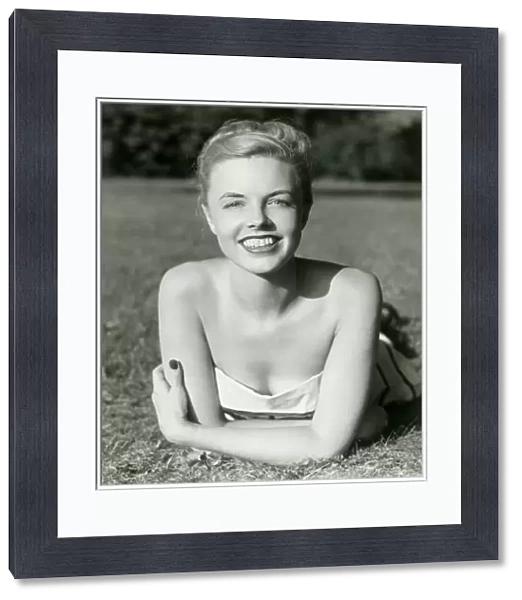 Young woman lying on grass, smiling, portrait
