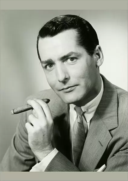 Businessman in studio holding cigar, (B&W), portrait