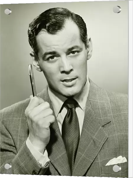Man holding ballpoint, posing in studio, (B&W), portrait