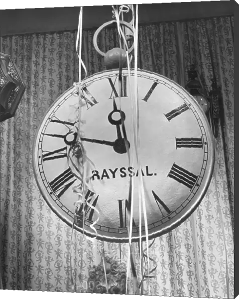 Wall clock covered in party streamers, (B&W)