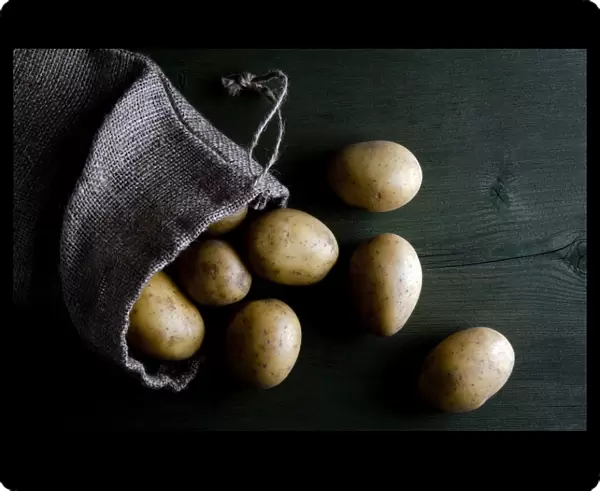 Potatoes in burlap sack on wood