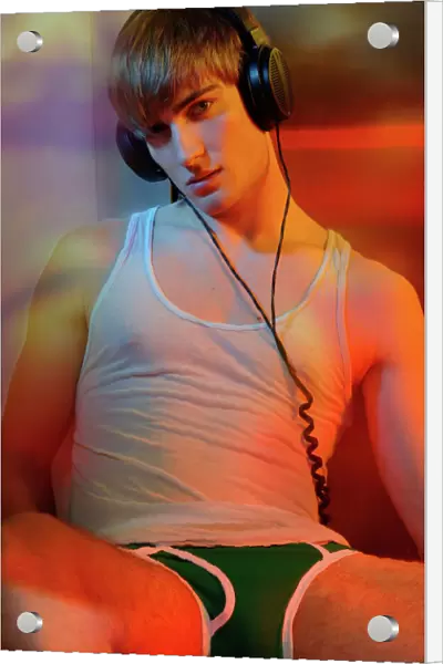 Young man in underwear with headphones in colorful light