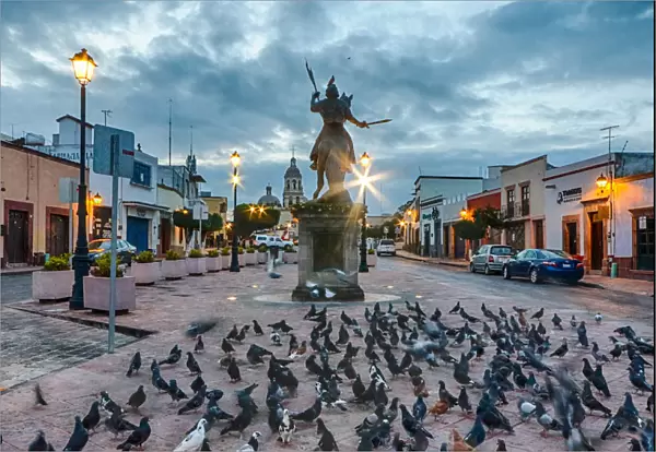 Ecuestre del ApAostol Santiago el Mayor statue, with many pigeons around it, in Queretaro, Mexico at dawn