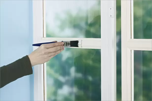 Person painting window frame with a brush