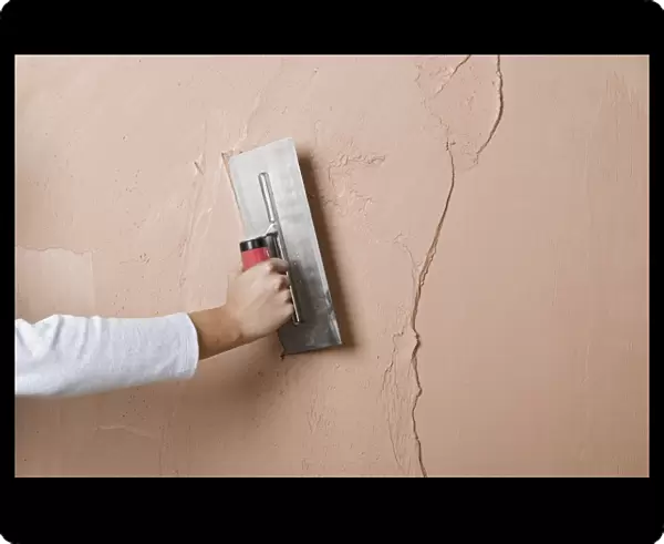 Applying a second layer of plaster to a wall using trowel