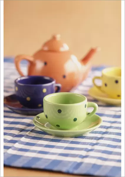 Teapot, cups and saucers on a chequered table cloth