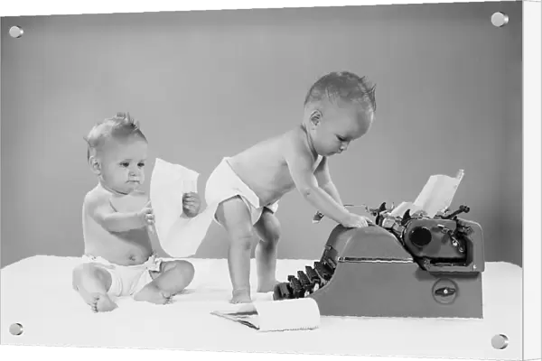 Baby standing at typewriter, twin seated behind looking at papers