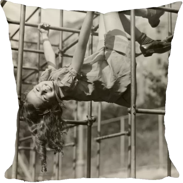 Child girl hanging upside down on jungle gym