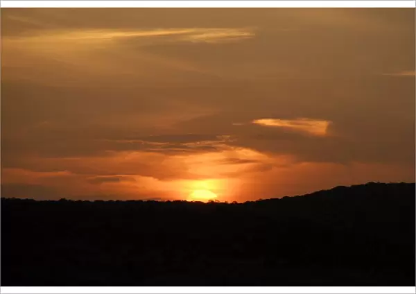 Orange sunset as sun sets behind hill, Phinda Private Game Reserve, KwaZulu-Natal, South Africa