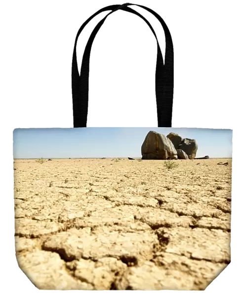 Dry Cracked Soil in Foreground with Boulders in Background