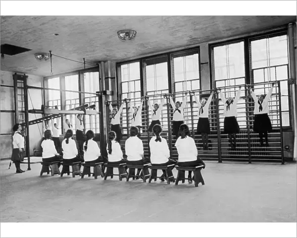 PE Class. A group of schoogirls attend a gym class, circa 1930
