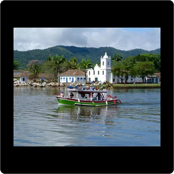 Colourful boat sailing with the pretty Brazilian town Paraty in the back ground