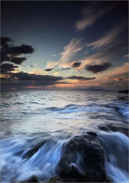 Water flowing over rocks on sea at sunset