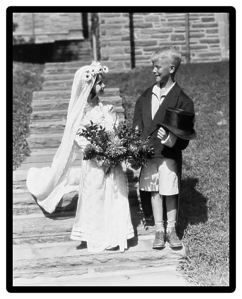 Boy and girl dressed up as bride and groom, outdoors on steps