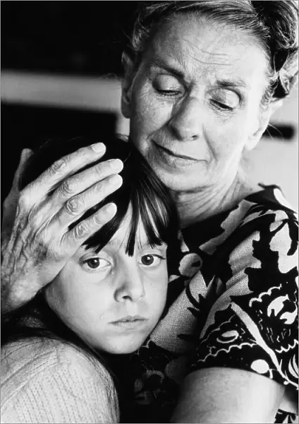Elderly woman embracing and comforting forlorn-looking granddaughter