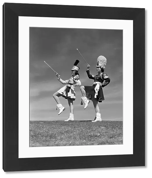 Two majorettes in uniform doing routine with batons