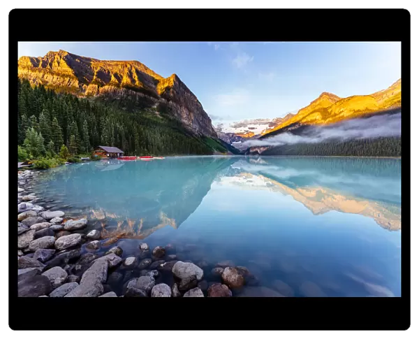 Lake Louise at sunrise, calm water and light on the mountain tops. Banff, Alberta, Canada