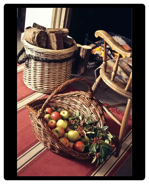 Big decorative basket of Coxs apples with sprays of ornamental berries by open fireplace